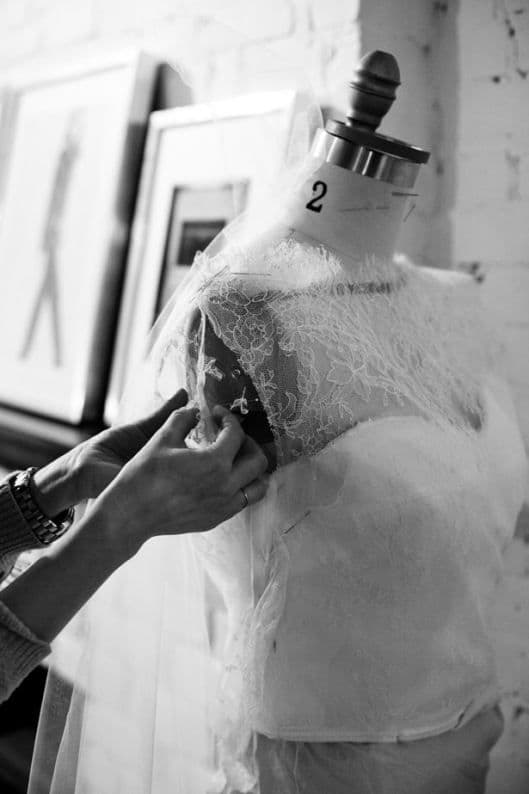 Hand pinning lace onto a bridal bodice on a dress form